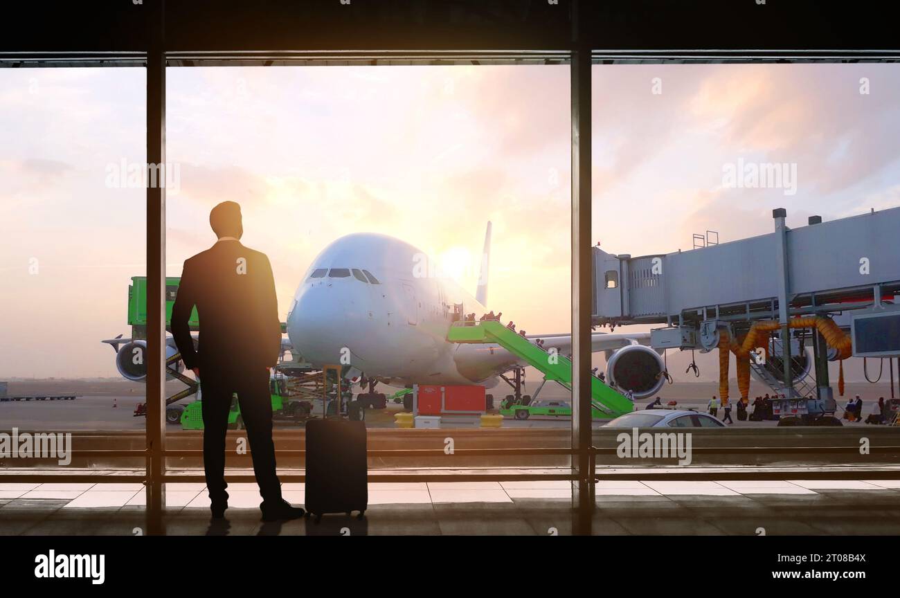 homme debout devant les fenêtres de vue du hall des départs de l'aéroport. Banque D'Images
