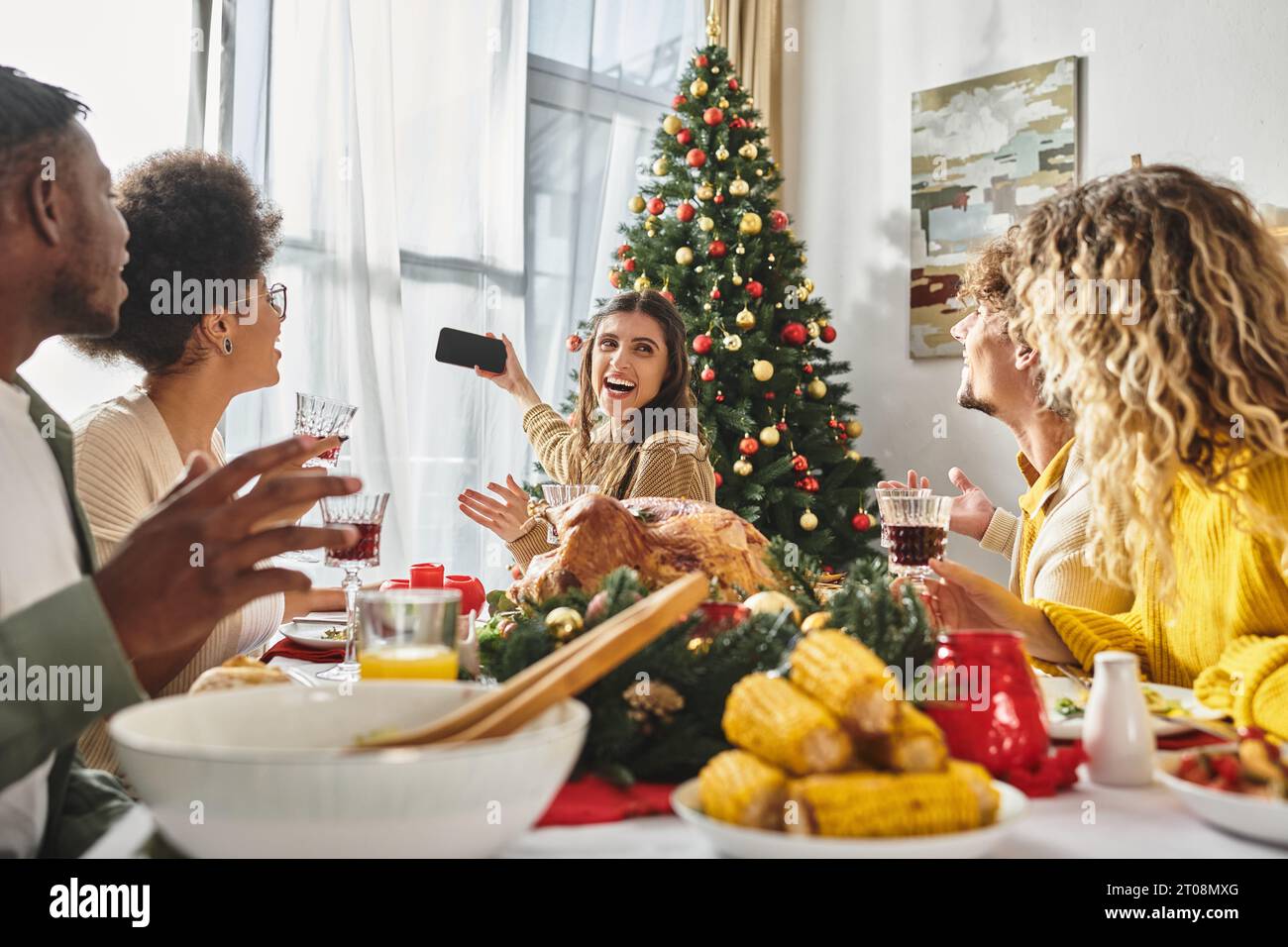 Membres de la famille multiethnique prenant des selfies tout en célébrant Noël ensemble à la fête des fêtes Banque D'Images
