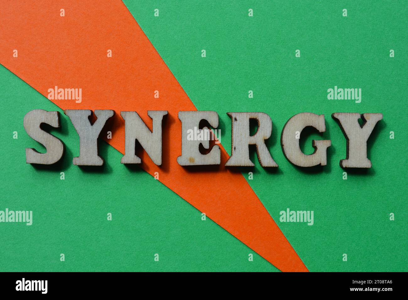 Synergy, mot en lettres de l'alphabet en bois isolé sur fond orange et vert Banque D'Images