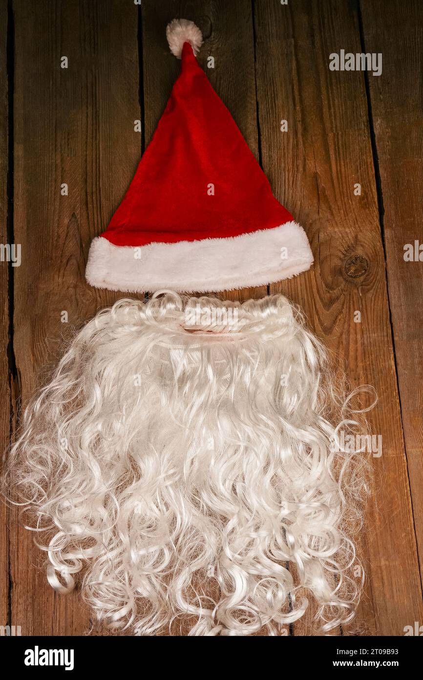Chapeau de Santa et barbe sur un fond en bois. Symbolisme des fêtes du nouvel an. Concept de Noël et de nouvel an. Changement de vêtements, changement d'image Banque D'Images