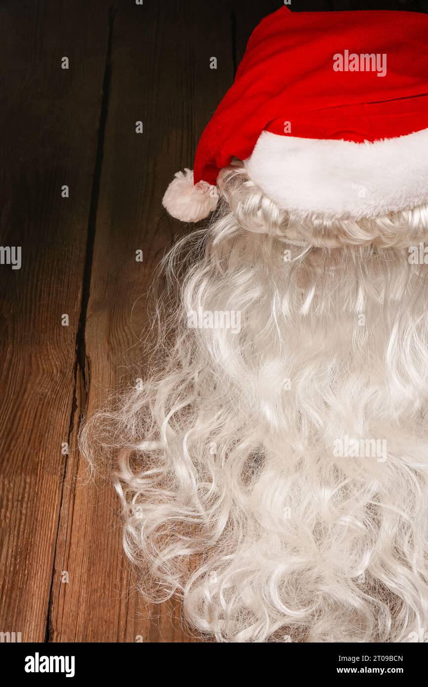 Chapeau de Santa et barbe sur un fond en bois. Symbolisme des fêtes du nouvel an. Concept de Noël et de nouvel an. Changement de vêtements, changement d'image Banque D'Images