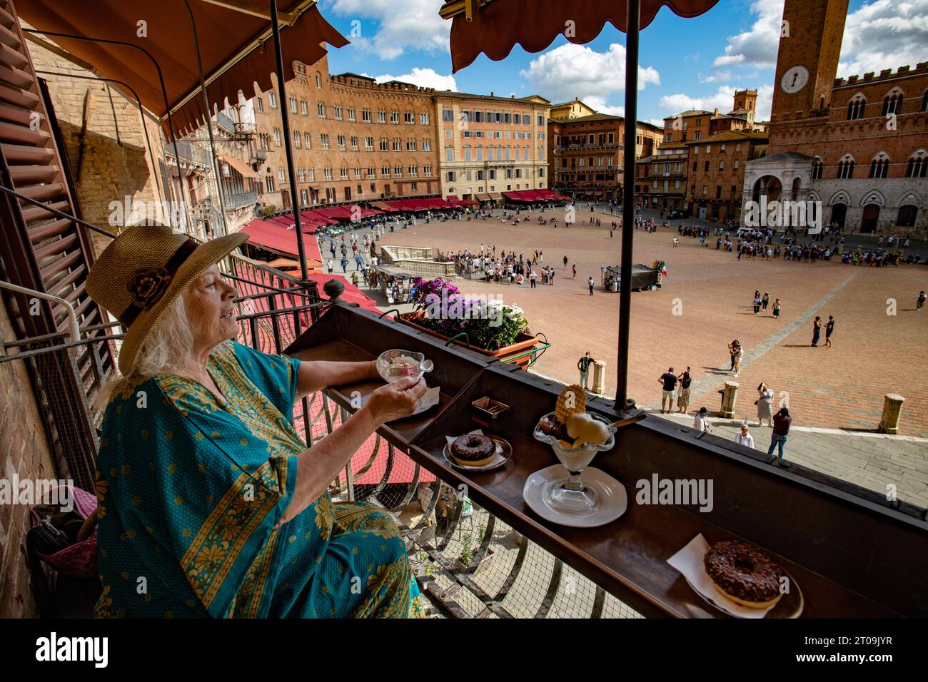 Sienne Toscane Italie septembre 2023 modèle libéré Femme apprécie la crème glacée et gâteau donnant sur la Piazza del Campo et la Tour Mangia (Torre de Banque D'Images