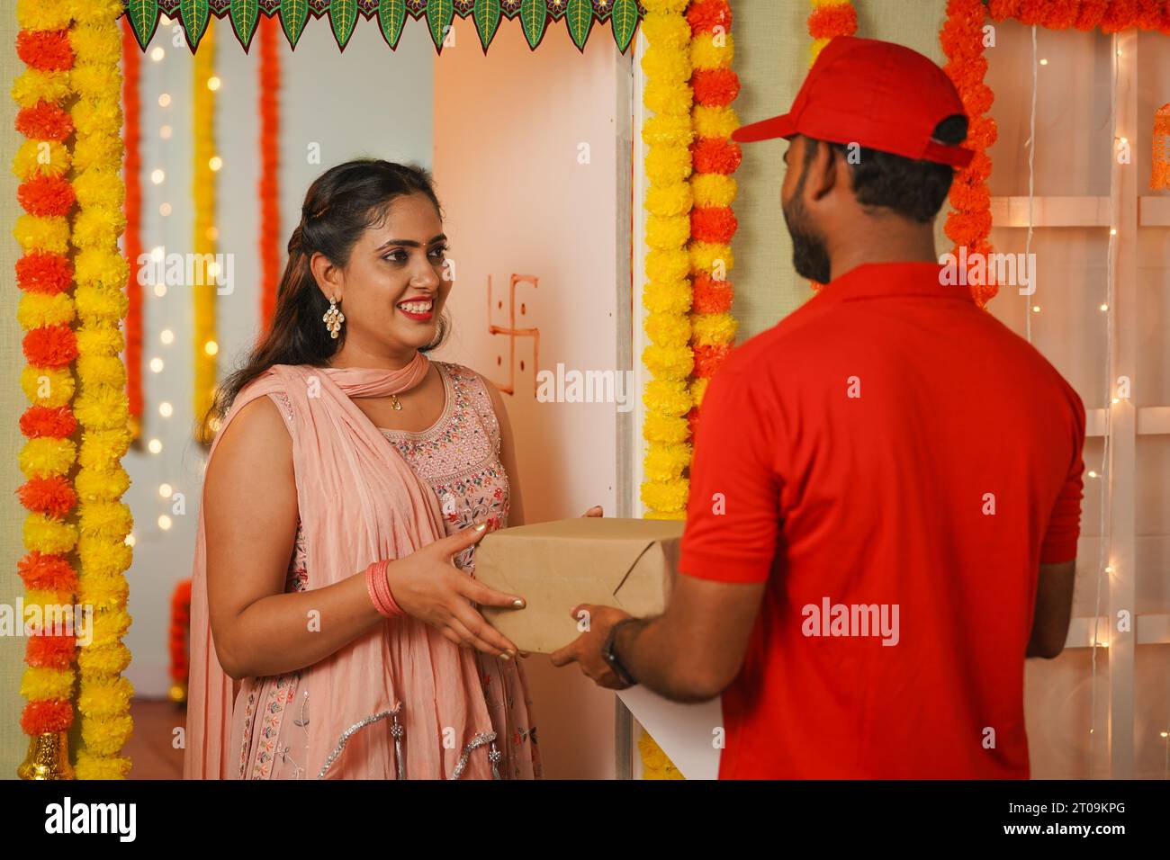 Heureuse fille excitée recevant la boîte de livraison du garçon de livraison pendant le jour du festival Diwali - concept de commande de commerce électronique festive, service de livraison rapide et Banque D'Images