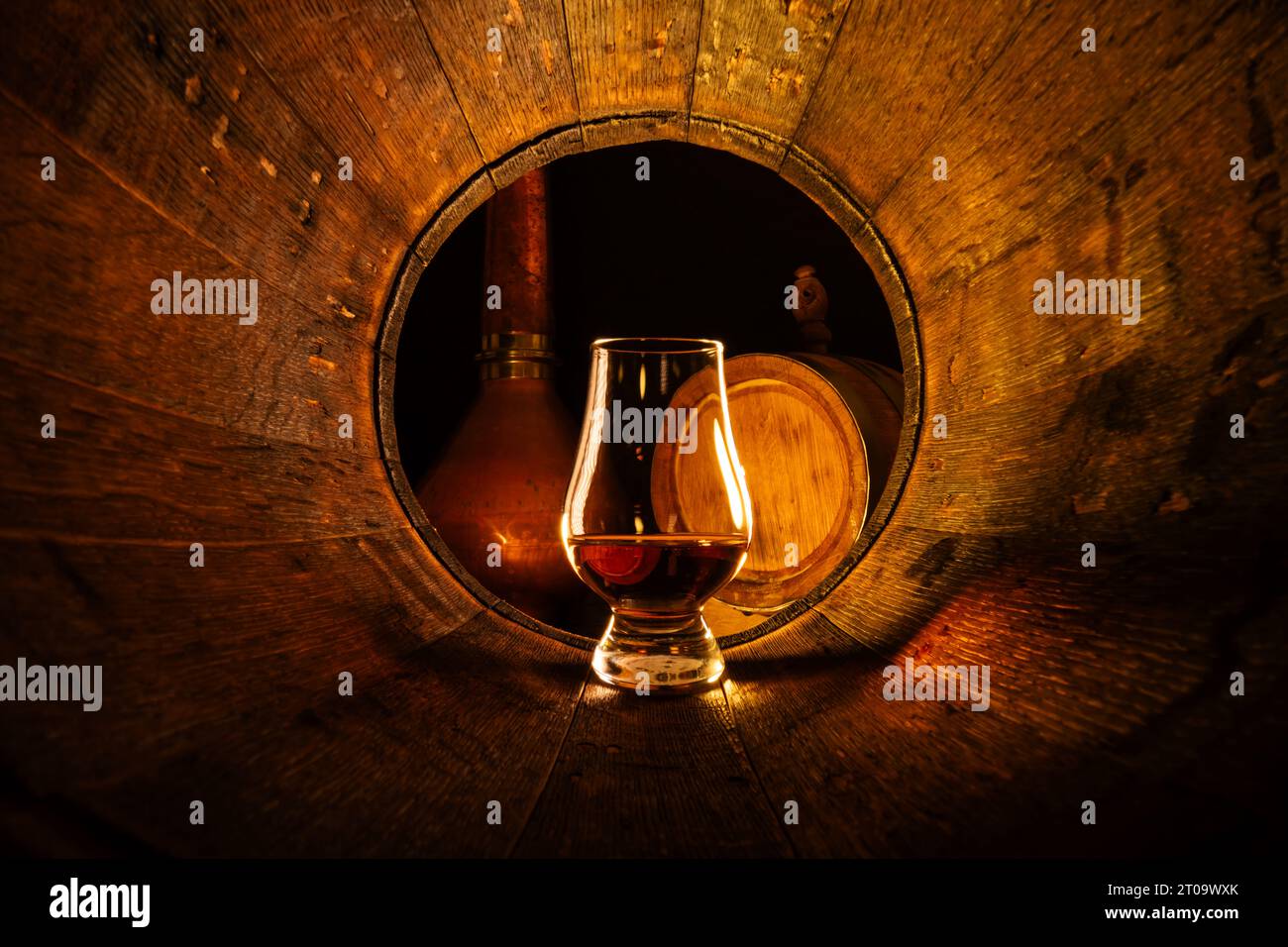 Un verre de whisky scotch en vieux fût de chêne. Cuivre alambic et petit baril sur fond. Concept traditionnel de distillerie d'alcool Banque D'Images