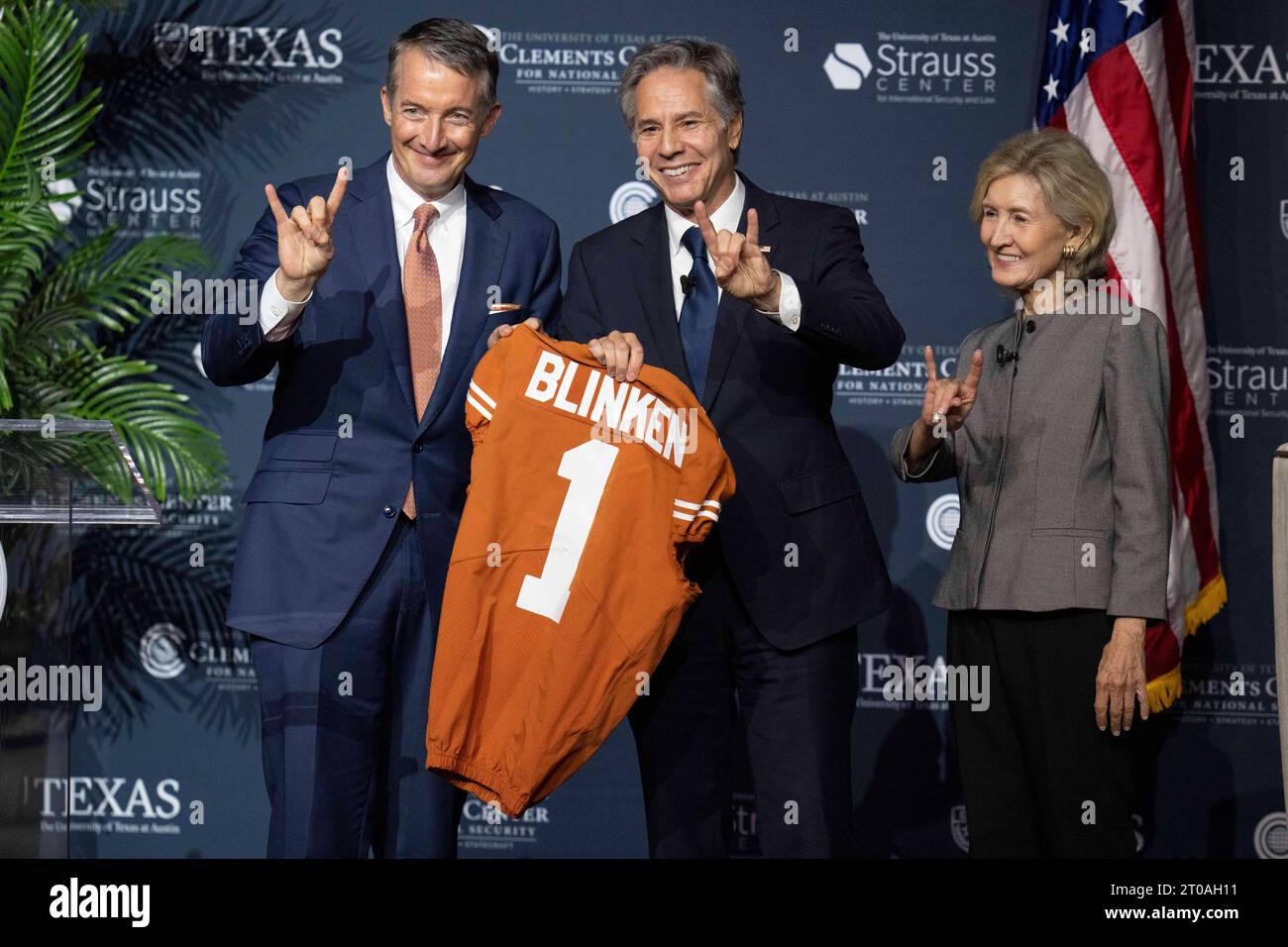 Austin Texas USA, octobre 4 2023 : le secrétaire d'État américain ANTONY BLINKEN (au centre) reçoit un maillot de football de l'Université du Texas à Austin Président JAY HARTZELL (à gauche) sous le regard de KAY BAILEY HUTCHISON. Blinken a dirigé une discussion sur la politique étrangère à l'Auditorium Hogg de l'Université du Texas. Les trois font clignoter le signal de la main ''Hook-emm' de l'Université du Texas. ©Bob Daemmrich Banque D'Images