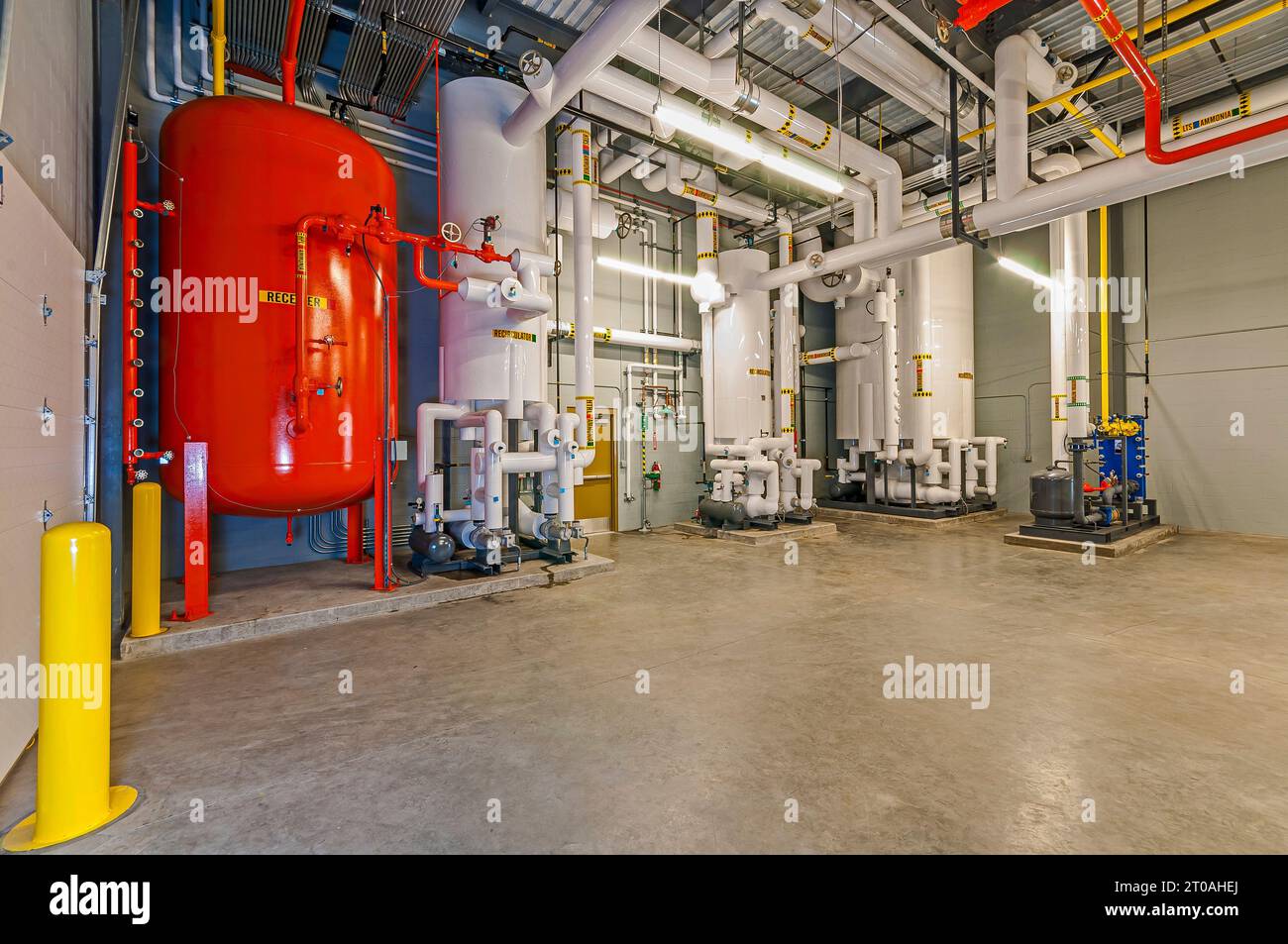 Réservoir récepteur vertical, machines et tuyauterie dans la salle du compresseur à cycle d'ammoniac d'un entrepôt frigorifique (réfrigération industrielle). Banque D'Images