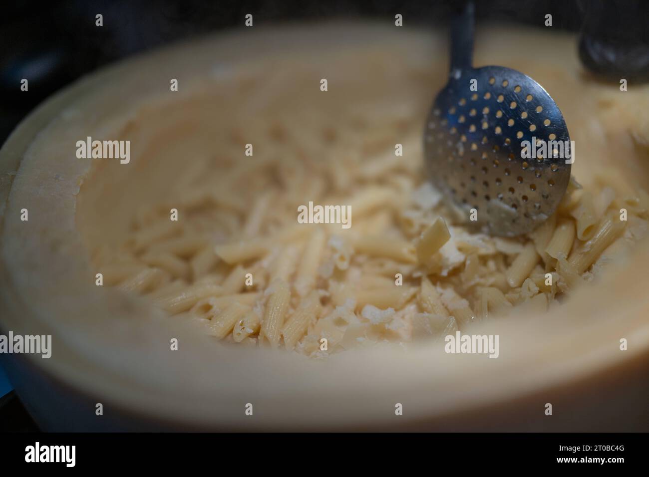 Pasta aus einem Parmesanlaib, Food, Deutschland, Rhénanie-Palatinat, 02.10.2023, das Bild zeigt eine Küchenszene, die eine kulinarische Tätigkeit darstellt. Der zentrale Fokus liegt auf einem Parmesanlaib mit Pasta, die mit einem Metalllöffel umgerührt wird. *** Pâtes à partir d'un pain de parmesan, alimentation, Allemagne, Rhénanie-Palatinat, 02 10 2023, l'image montre une scène de cuisine représentant une activité culinaire. l'accent est mis sur une miche de parmesan avec des pâtes agitées avec une cuillère en métal Credit : Imago/Alamy Live News Banque D'Images