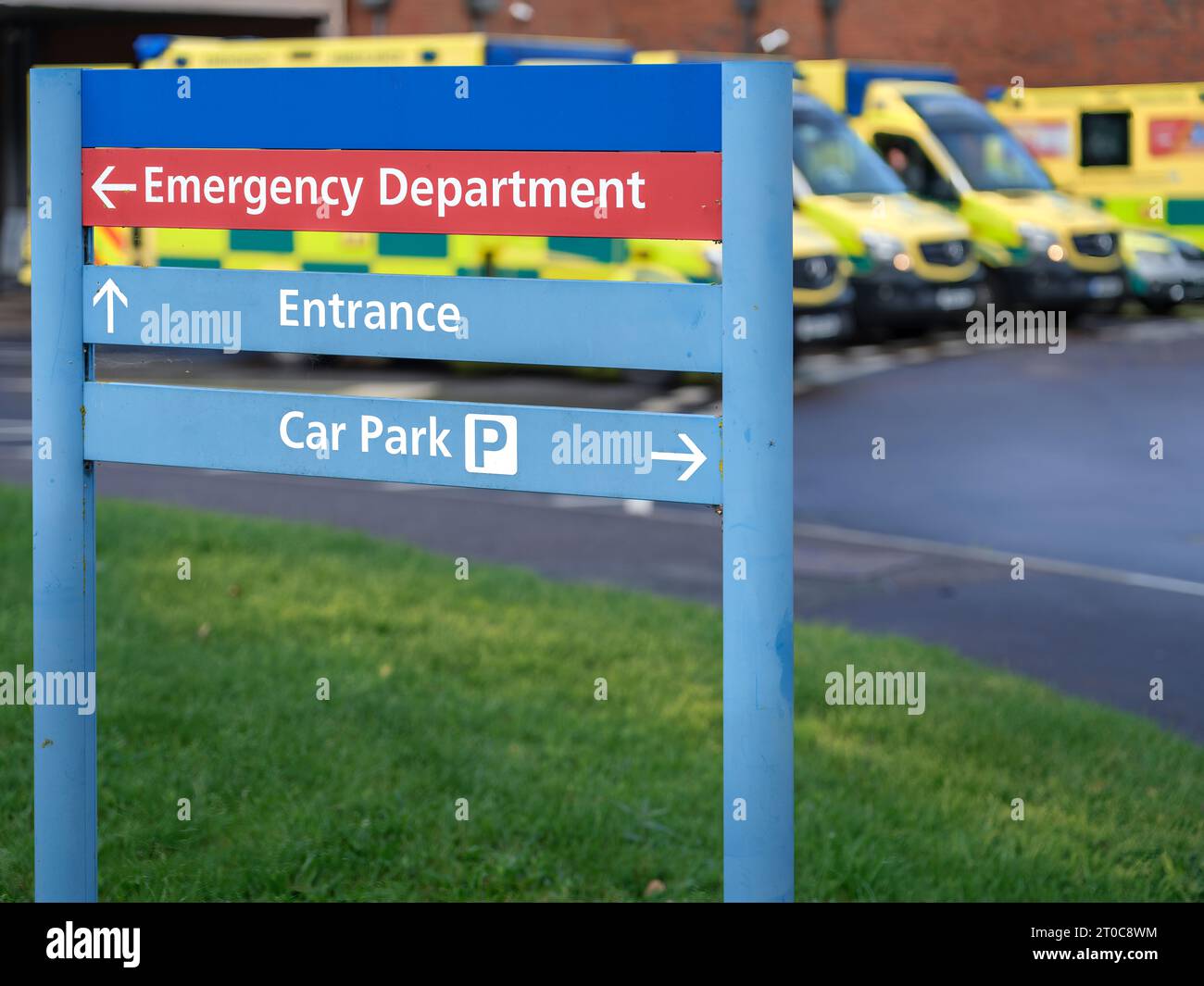 Un panneau de service des urgences avec une rangée d'ambulances dans une rangée derrière. Banque D'Images