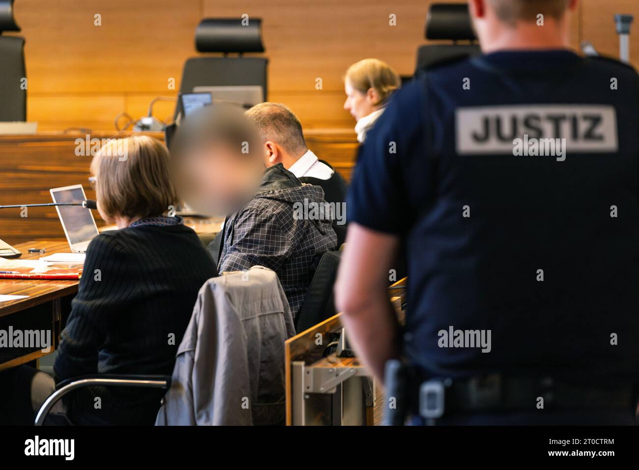 06 octobre 2023, Bade-Württemberg, Fribourg : le défendeur (2e à partir de la gauche) est assis entre un interprète et son avocat, tandis qu'un huissier de justice peut être vu au premier plan. Le Polonais, âgé de 26 ans, aurait mortellement blessé une femme de 89 ans à Herbolzheim à la fin du mois d'octobre 2022 et l'aurait enfermée dans une cave. Dans l'appartement d'un couple très âgé, où il travaillait comme préposé aux soins à domicile depuis le 7 octobre 2022 et où il avait aussi vécu, il aurait disposé des bijoux prêts à être volés. Ce faisant, il a été troublé par la victime de 89 ans, qui a pu le faire Banque D'Images