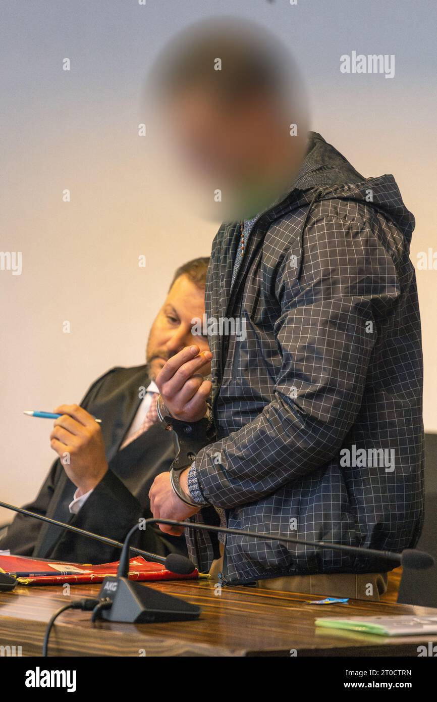 06 octobre 2023, Bade-Württemberg, Fribourg : le défendeur est menotté à côté de son avocat de la défense devant le tribunal régional de Fribourg. Le Pole, âgé de 26 ans, aurait mortellement blessé une femme de 89 ans à Herbolzheim à la fin du mois d'octobre 2022 et l'aurait enfermée dans une cave. Dans l’appartement d’un couple très âgé, où il travaillait comme préposé aux soins à domicile depuis le 7 octobre 2022, et où il vivait également, il aurait disposé des bijoux prêts à être volés. Ce faisant, il a été troublé par la victime âgée de 89 ans, qui a pu avertir la police avant la défenda Banque D'Images