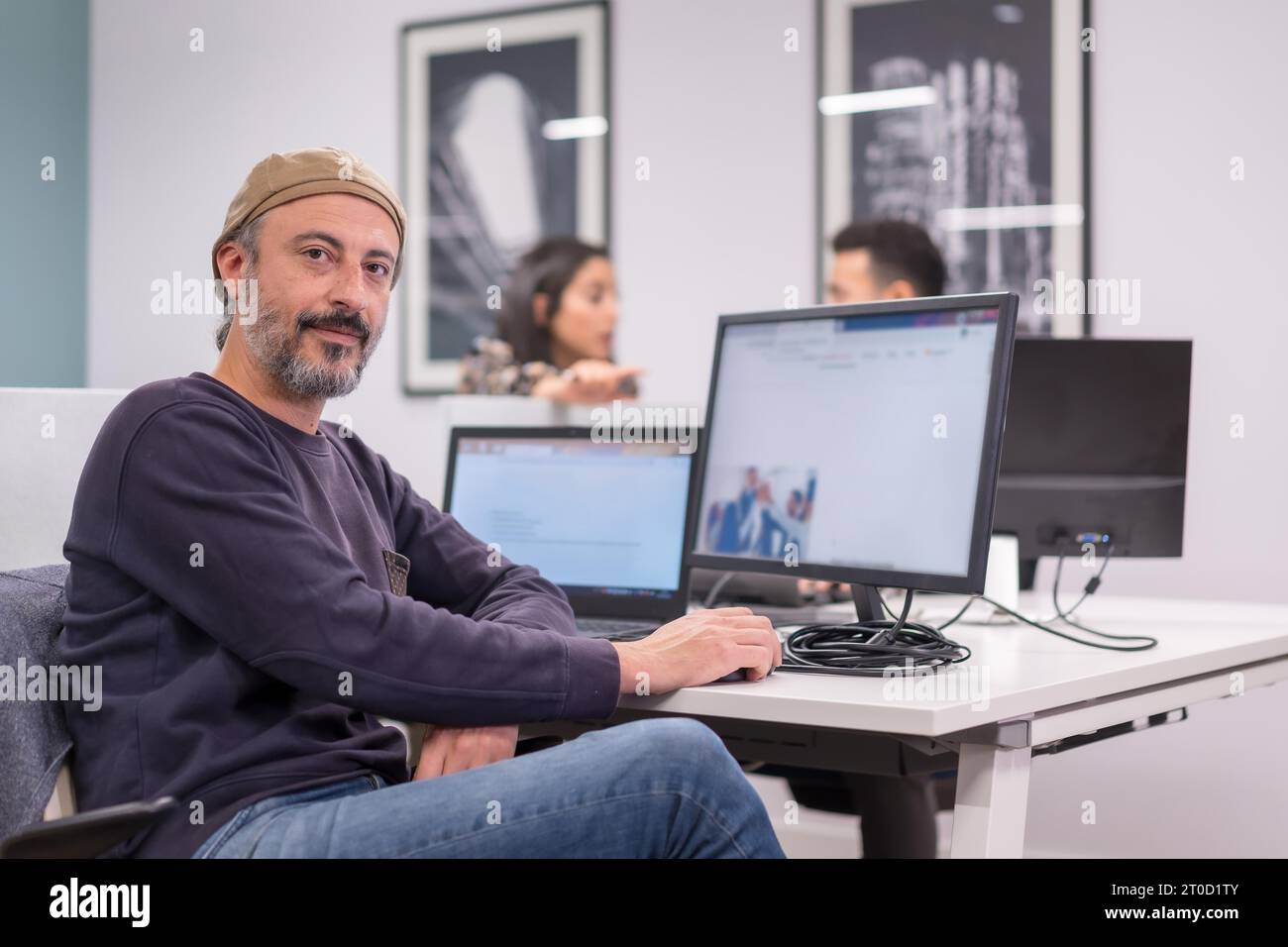 Portarit d'un homme fier souriant à la caméra tout en travaillant dans un bureau de co-working moderne Banque D'Images