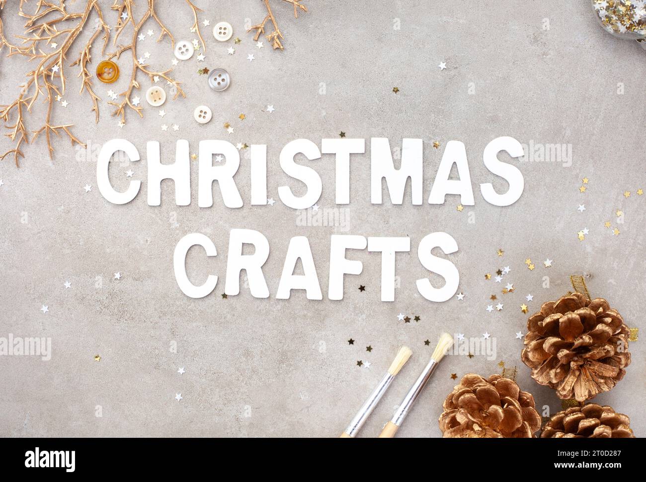 Artisanat de Noël en lettres blanches sur fond gris marbré avec des morceaux de décoration dorés Banque D'Images
