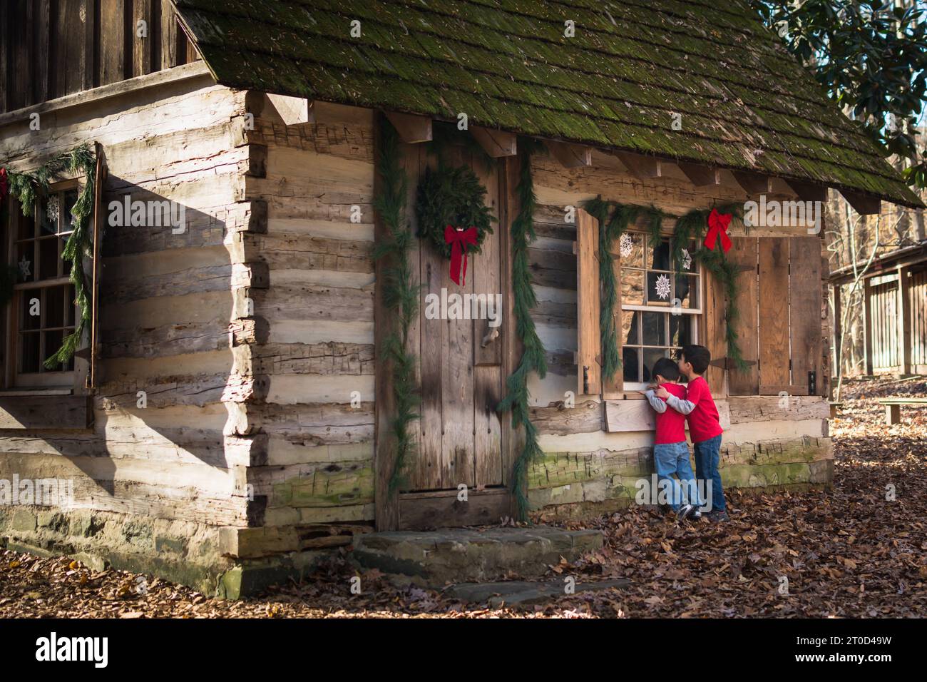 Garçons jetant un coup d'œil dans la fenêtre de la cabine décorée pour les vacances de noël. Banque D'Images