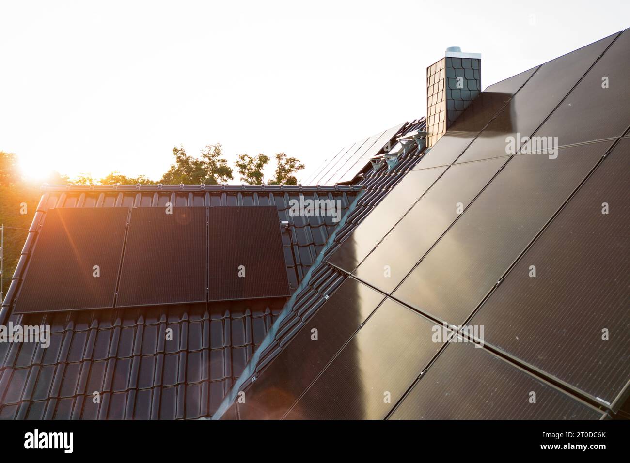 Panneaux solaires sur le toit d'une maison unifamiliale durable au coucher du soleil Banque D'Images