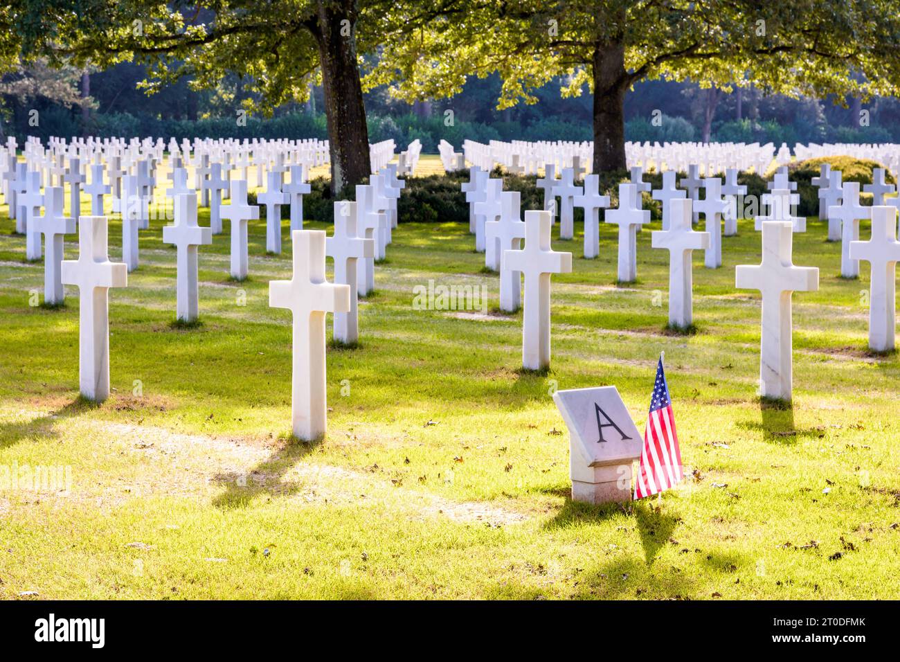 Croix de marbre blanc dans le cimetière américain de Normandie et mémorial à Colleville, un cimetière militaire de la Seconde Guerre mondiale près d'Omaha Beach, avec un drapeau américain. Banque D'Images
