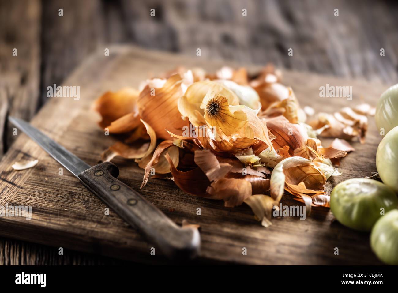 Peaux d'oignons empilées sur une planche à découper à côté d'oignons nettoyés. Banque D'Images