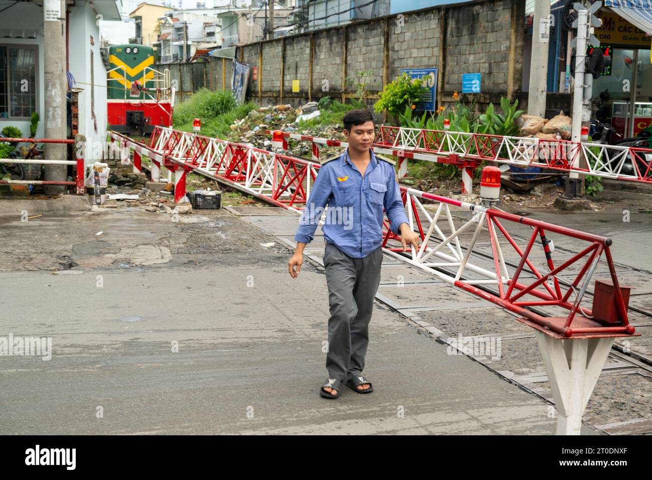 Fermeture des portes pour un train de passage au célèbre passage à niveau de la voie ferrée de Saigon, Ho Chi Minh-ville, Vietnam Banque D'Images