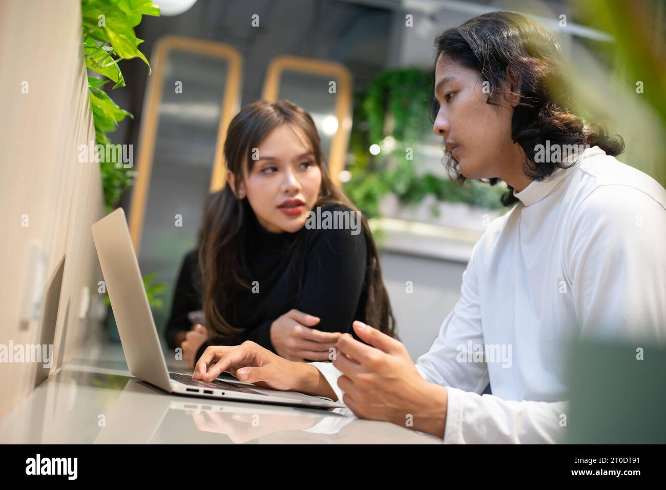 Collègues d'affaires travaillant sur ordinateur portable dans l'espace de vie dans le bureau, l'équipe de collègues parlant. Banque D'Images
