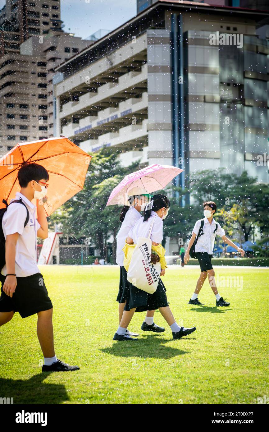 Les étudiants universitaires thaïlandais se promènent sur la pelouse principale de l'université Srinakharinwirot Bangkok, en Thaïlande, et se mouillent par les arroseurs de jardin. Banque D'Images