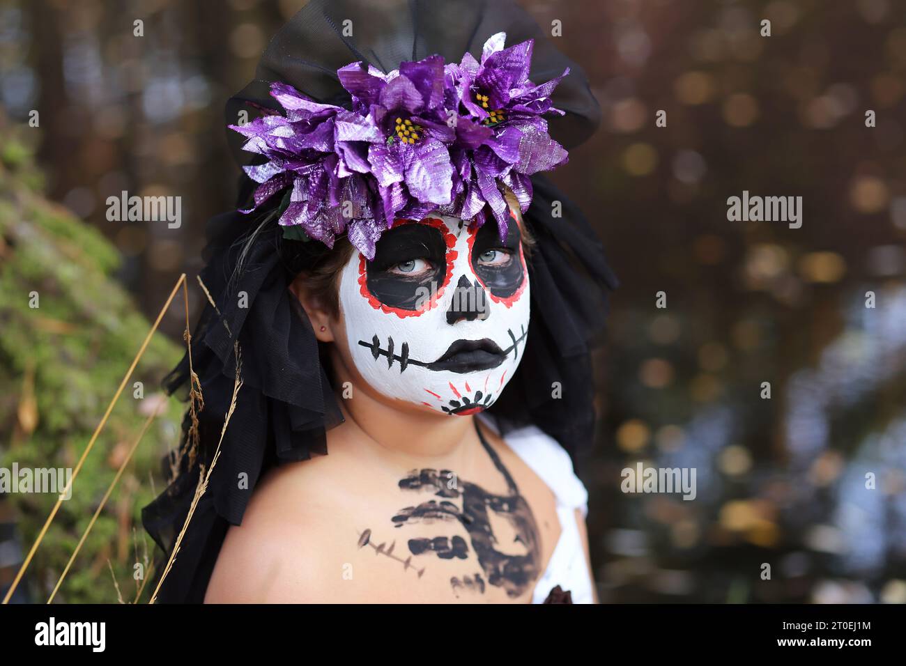 Fille sérieuse dans la tenue de mariée morte effrayante avec citrouille Jack o lanterne regardant la caméra tout en se tenant dans la nature pendant les vacances d'Halloween Banque D'Images