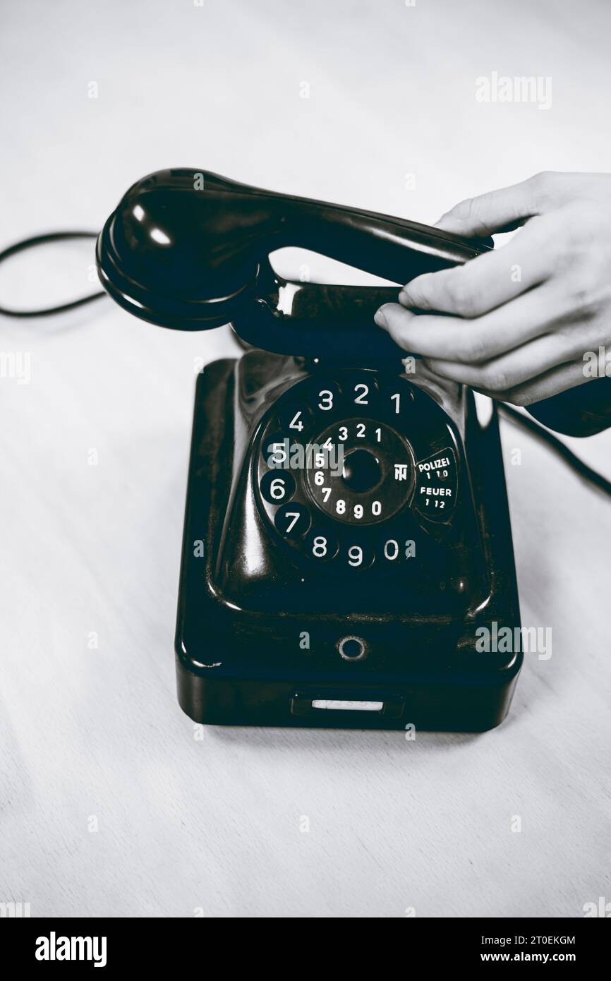 Une main femelle saisit le récepteur d'un vieux téléphone à cordon Banque D'Images