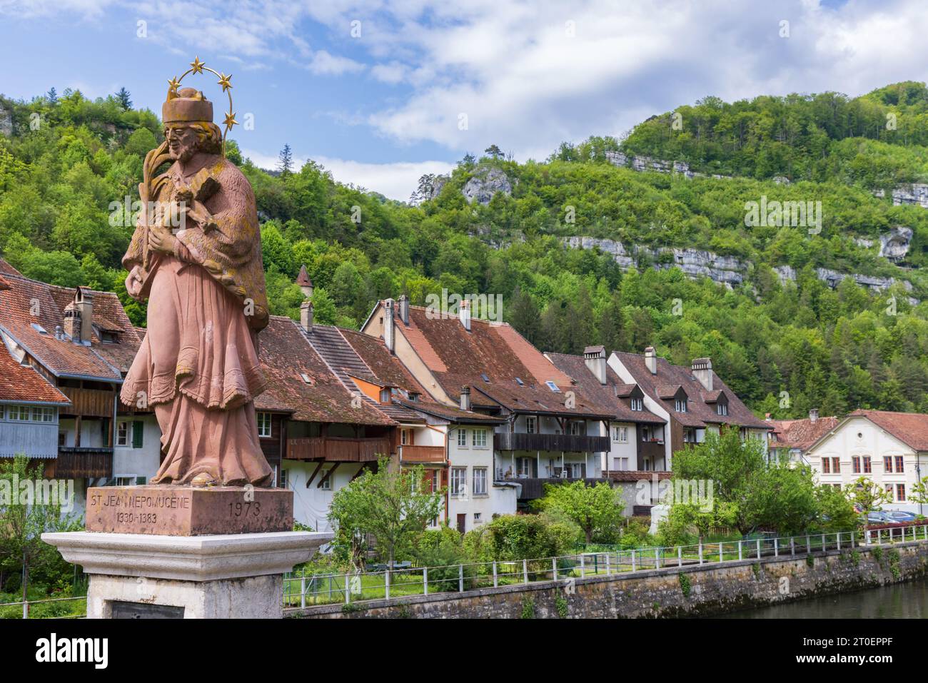 St-Ursanne, Suisse - 15 mai 2023 : Pont d'entrée avec sculpture historique de saint traversant le Doubs dans le village pittoresque de Saint-Ursanne dans le canton du Jura destraire Porrentruy dans la Suisse Banque D'Images