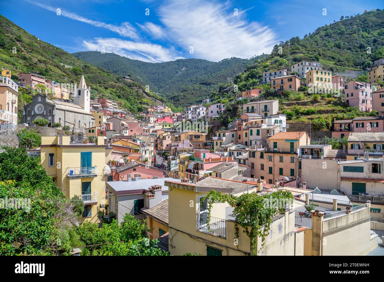 Italie, Ligurie, province de la Spezia, Riomaggiore, maisons de la ville côtière de Cinque Terre, vue vers la montagne avec l'ancienne église de San Giovanni Battista Banque D'Images