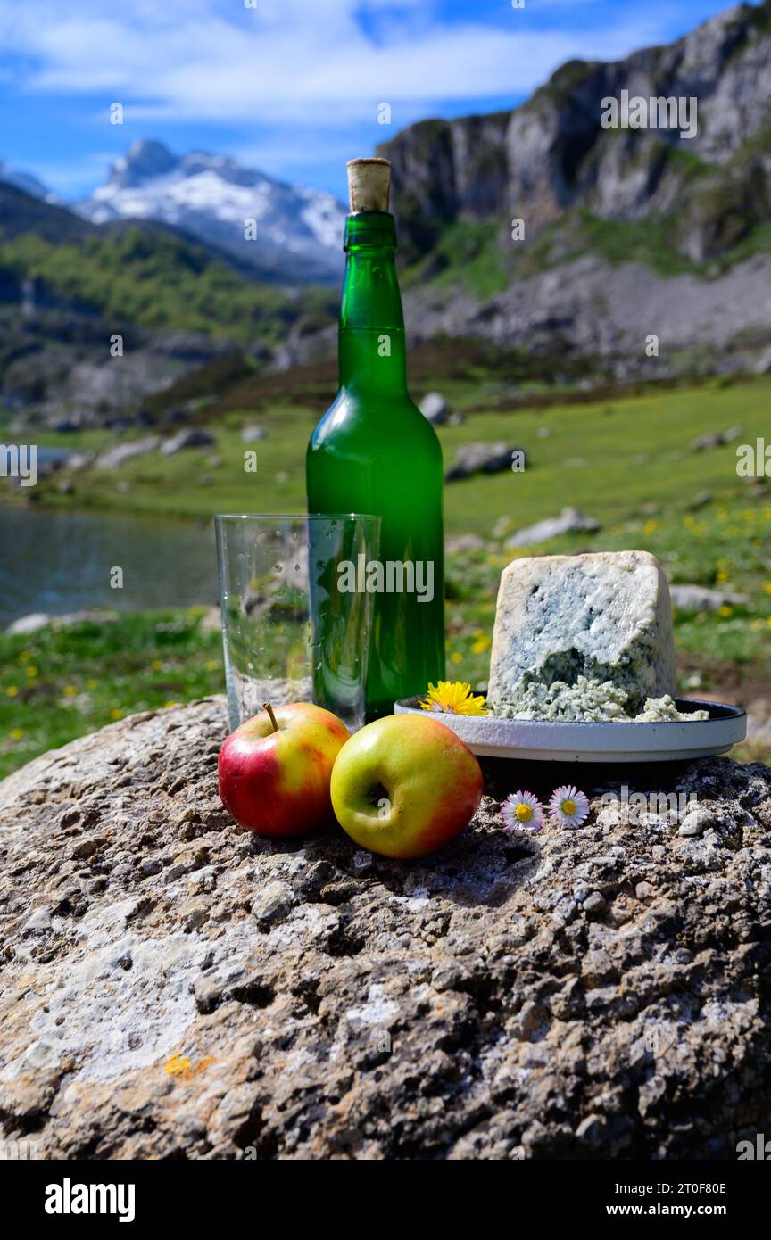 Bouteille verte et verre de cidre naturel des Asturies à base de pommes fermentées, fromage bleu de vache des Asturies cabrales avec vue sur les lacs et les sommets de Covadonga o Banque D'Images