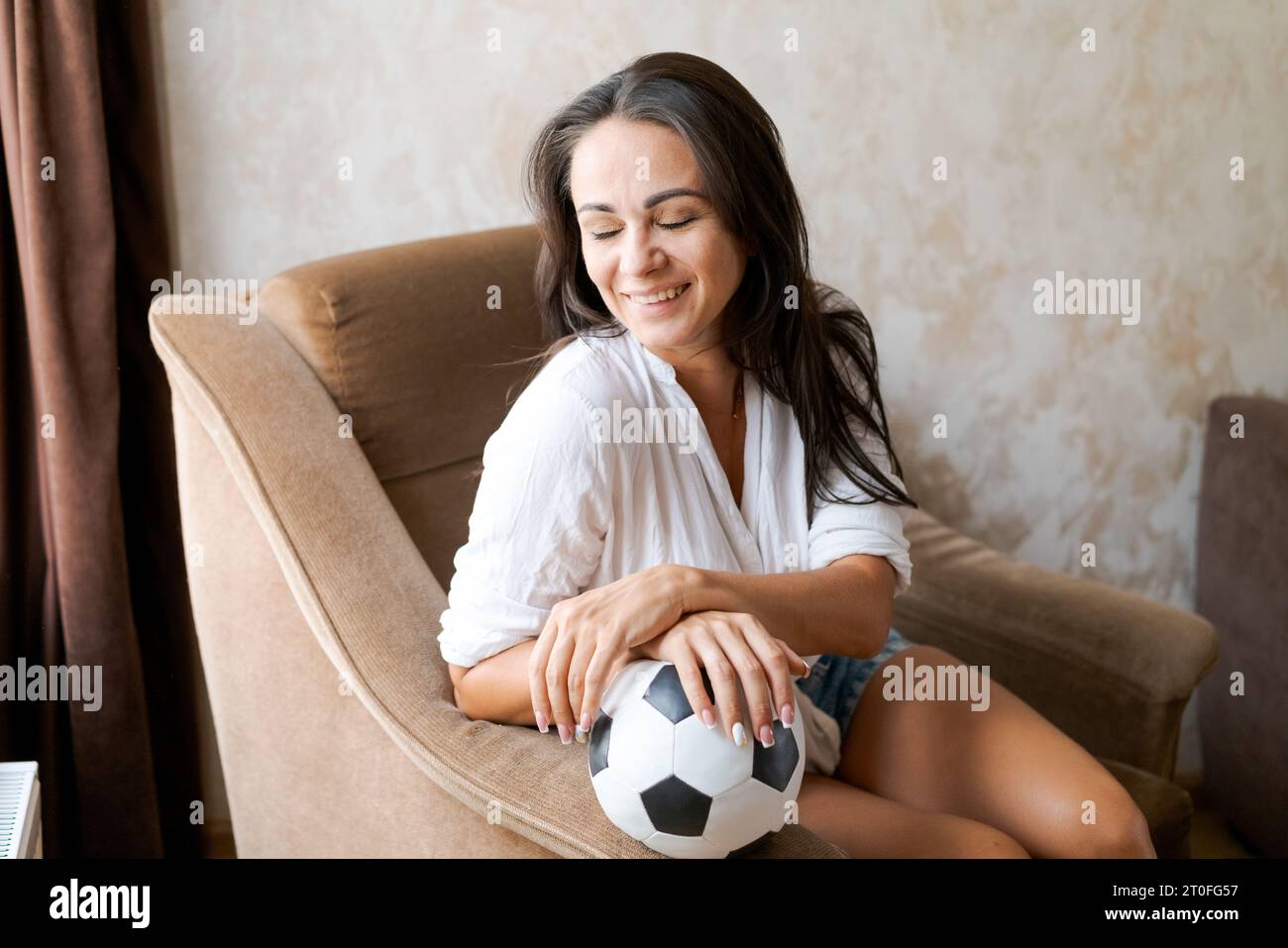 femme assise sur une chaise tenant un ballon de football dans sa main Banque D'Images