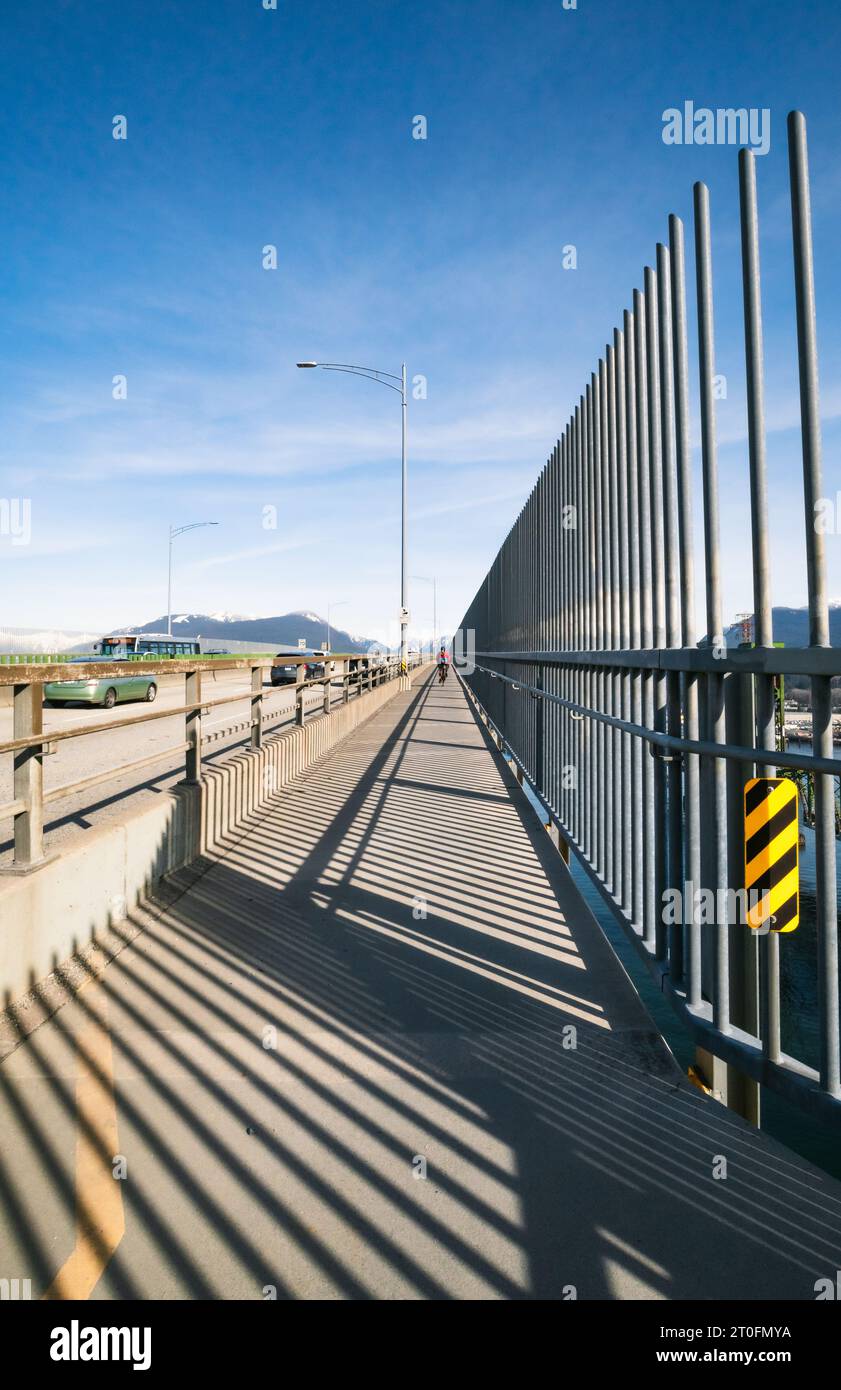 Piste piétonne cyclable à côté de la piste des véhicules sur le pont avec barrière anti-suicide sur la journée ensoleillée d'hiver. Pont commémoratif des ferronniers ou second Narrows Cr Banque D'Images