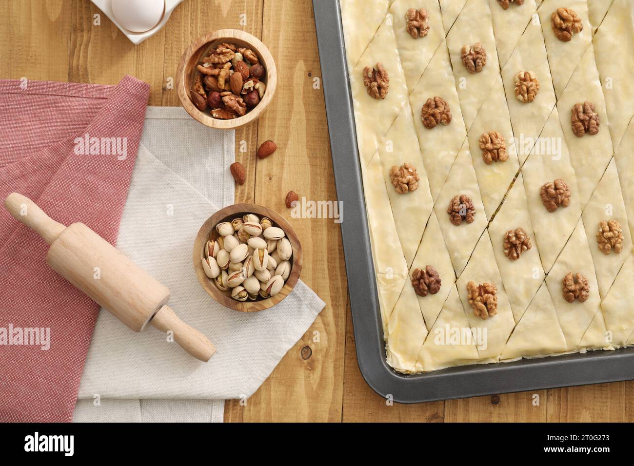 Faire de délicieux baklava. Moule à pâtisserie avec de la pâte et des ingrédients sur la table en bois, pose à plat Banque D'Images