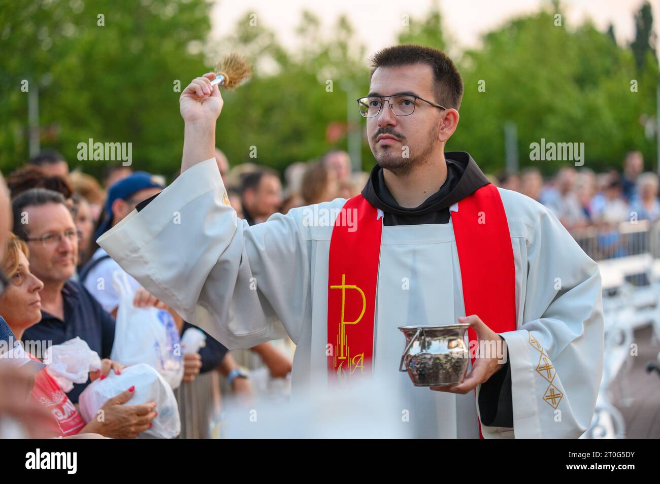 Un prêtre bénit les articles religieux des fidèles après la Messe du soir à Medjugorje. Banque D'Images