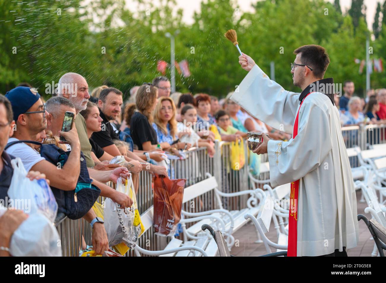 Un prêtre bénit les articles religieux des fidèles après la Messe du soir à Medjugorje. Banque D'Images
