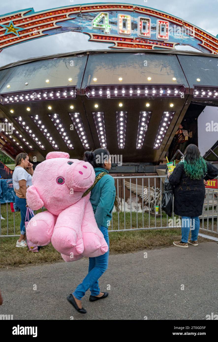 2023 Virginia State Fair, Doswell, va - Une femme escortant son prix à domicile marche devant le tour Starship 400 Banque D'Images