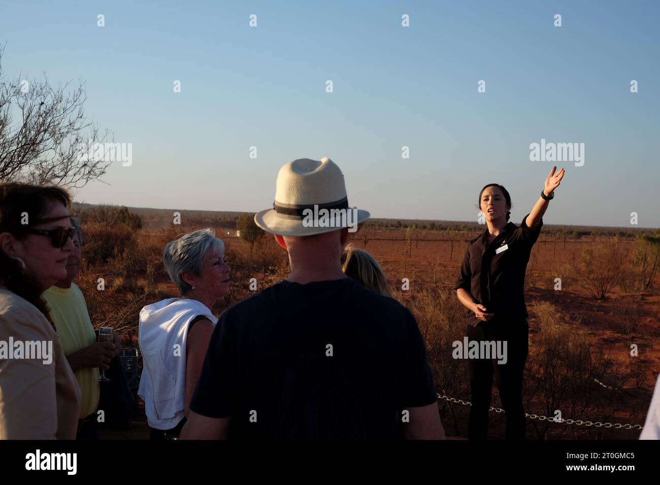 Une jeune femme annonce aux invités les divertissements nocturnes sur la plate-forme d'observation du coucher de soleil d'Uluru, avant le dîner Sounds of Silence Banque D'Images