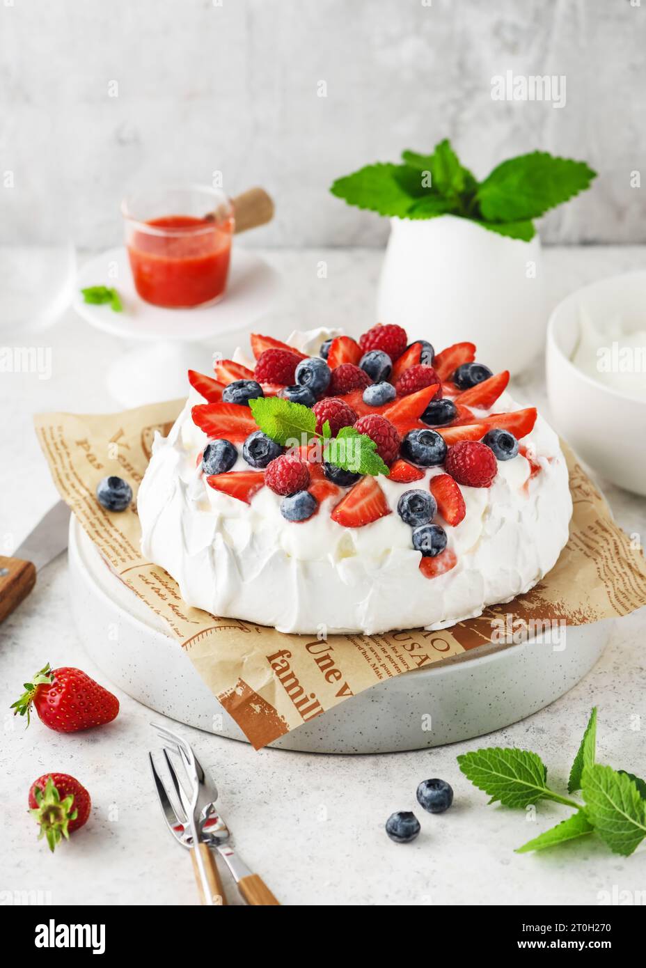 Gâteau Pavlova sucré et crémeux maison avec baies fraîches, crème vanille et sauce fraise. Recette de dessert meringue d'été, menu. Espace de copie. Banque D'Images