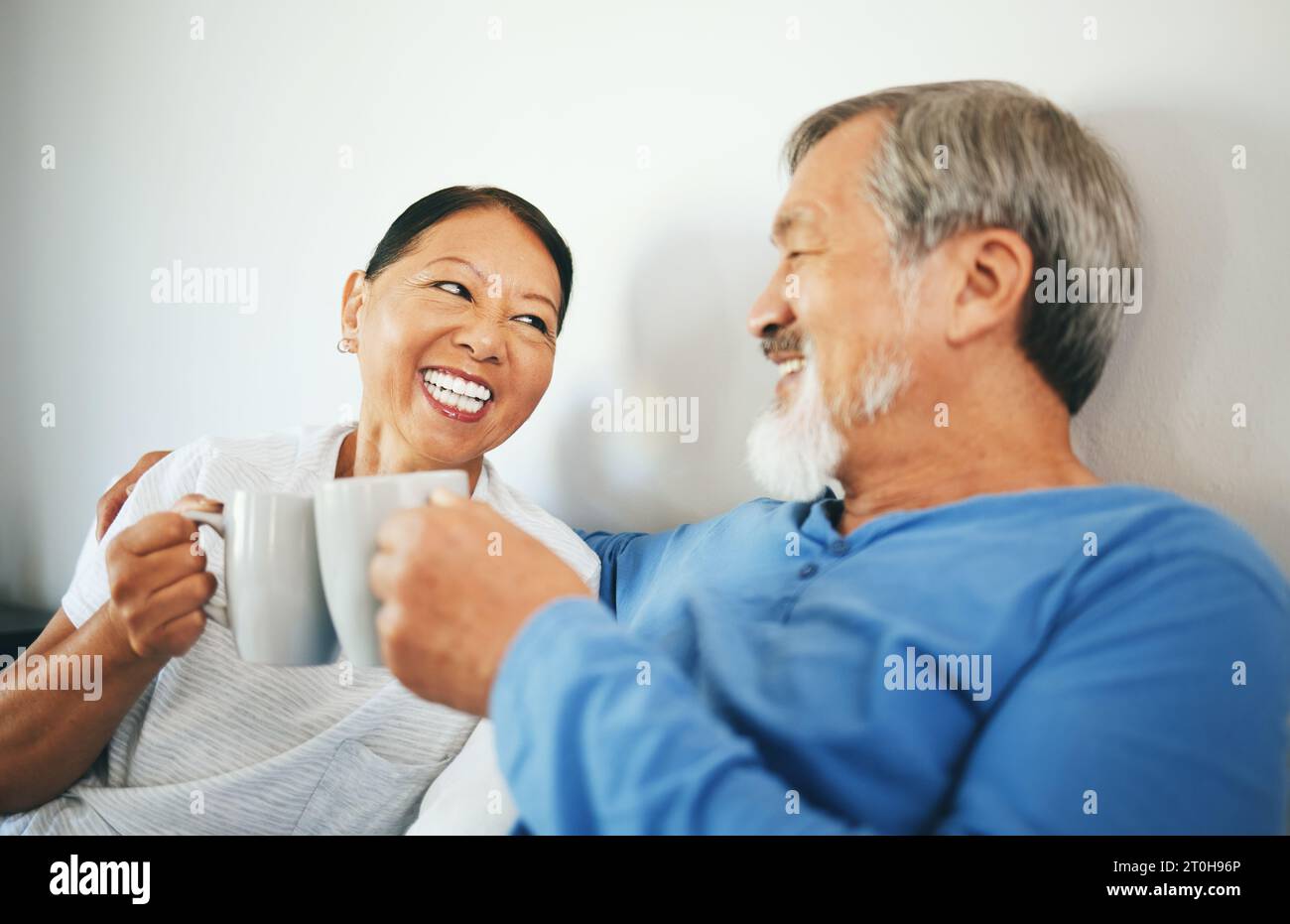Senior, café ou couple heureux dans la chambre à coucher à la maison de liaison ou parler dans le mariage ensemble. Acclamations, boire du thé du matin ou femme asiatique riant avec un Banque D'Images