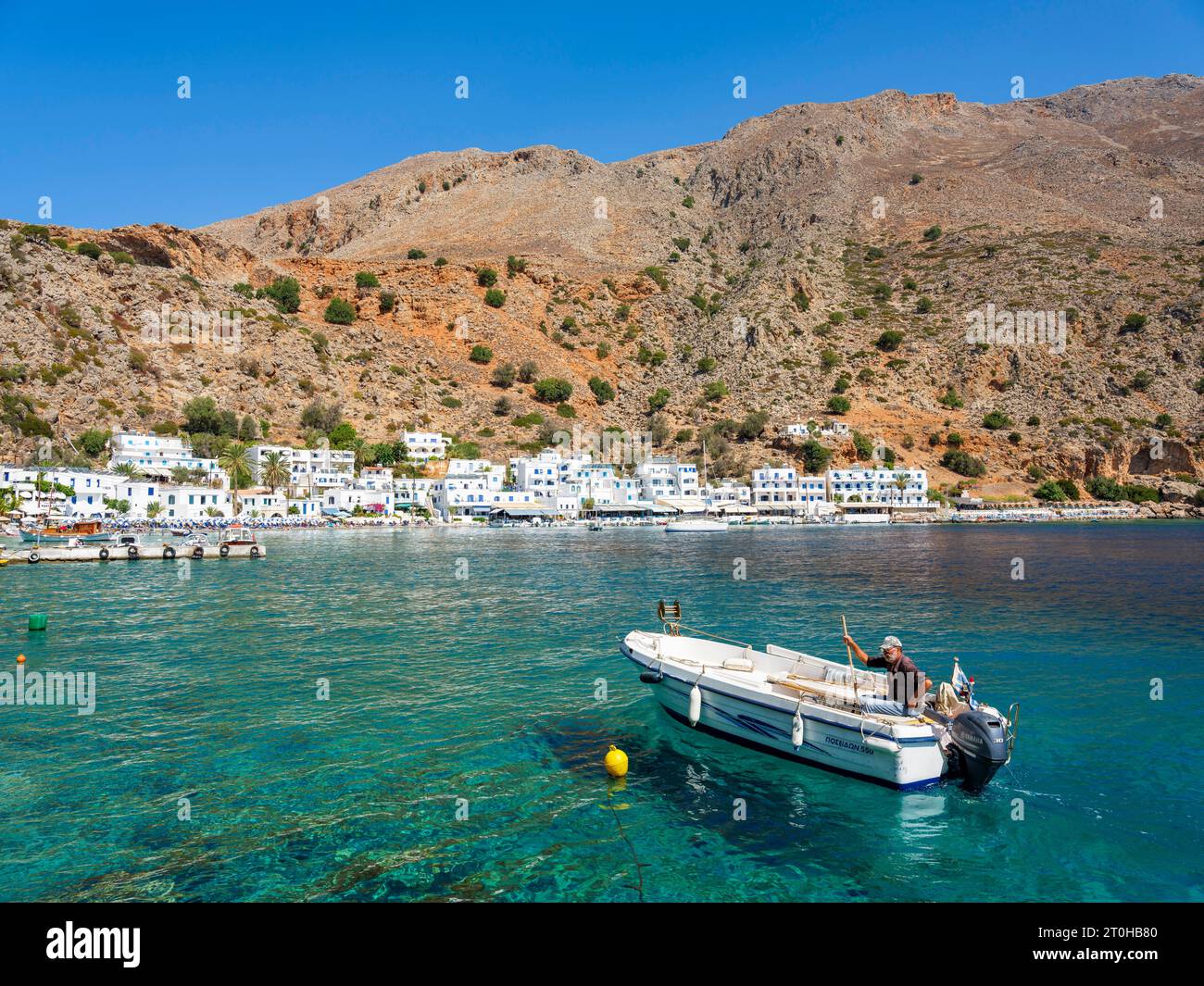 Petit bateau de pêche dans le port de Loutro au-dessous d'une montagne rocheuse, Chora Skafion, Crète, Grèce Banque D'Images
