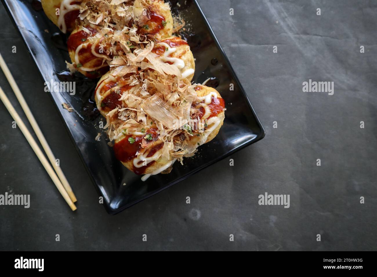 Le takoyaki est un aliment japonais, à base de pâte de farine de blé, de viande de poulpe ou d'autres garnitures, servi avec sauce, mayonnaise et garniture sous forme de ka Banque D'Images