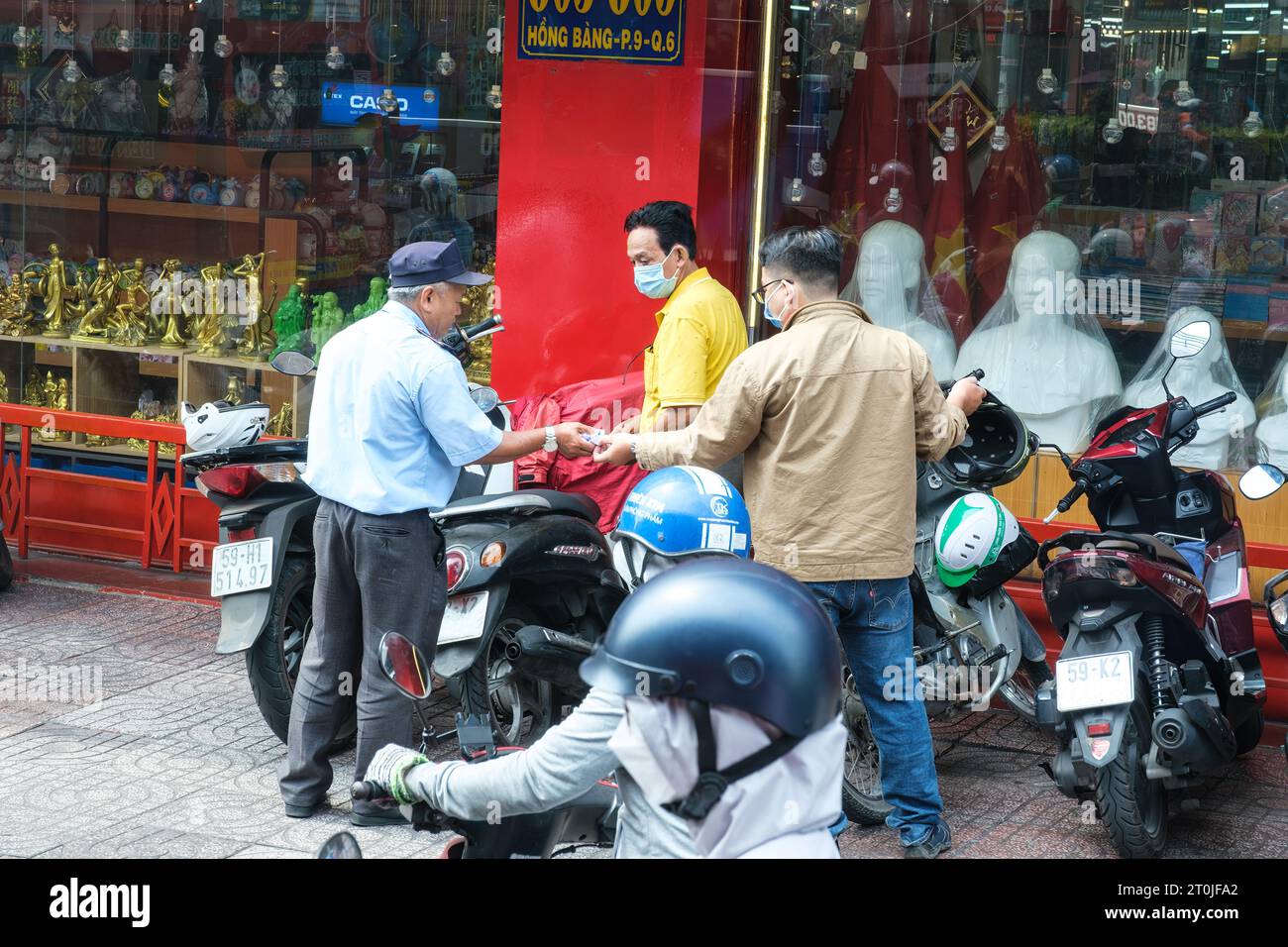 Ho Chi Minh, Vietnam. Préposé au stationnement payant pour garer la moto sur le trottoir. Banque D'Images