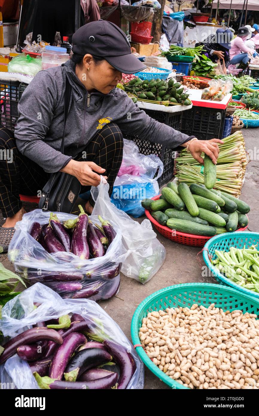 Hoi an, Vietnam. Femme vendant des aubergines et des concombres sur le marché. Banque D'Images