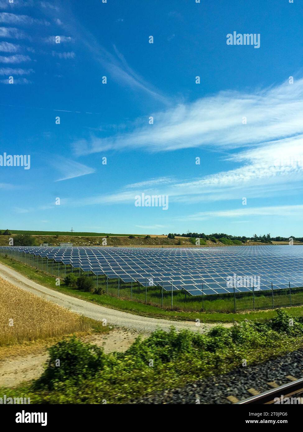 Un système de panneaux solaires photovoltaïques à grande échelle est situé au milieu d'un champ herbeux, avec un ciel bleu vibrant au-dessus Banque D'Images