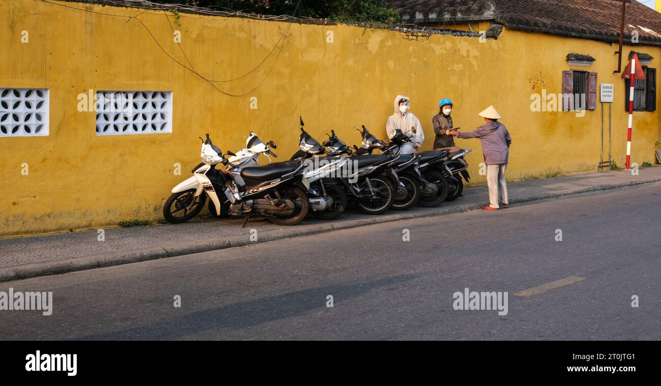 Hoi an, Vietnam. Préposé au stationnement collectant des frais pour garer la moto sur le trottoir. Banque D'Images