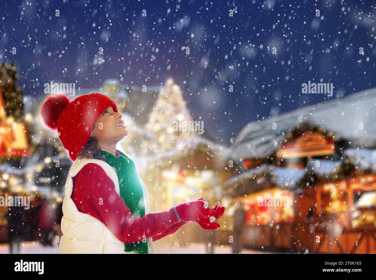 Enfant à la foire de Noël dans la neige. Petite fille au marché de Noël dans la ville européenne. Boutiques et restaurants traditionnels de vacances. Les enfants apprécient les vacances d'hiver. Banque D'Images