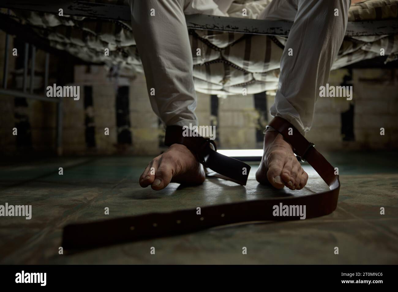 Gros plan pieds nus jambes de psycho homme lié avec ceinture brune serrée Banque D'Images