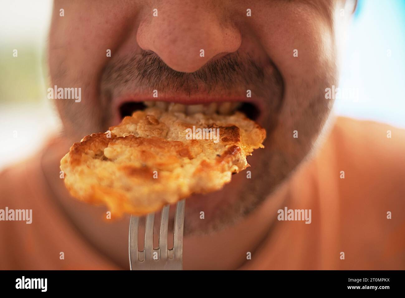 homme prenant une bouchée d'un morceau de viande de poulet frit d'une fourchette. dîner Banque D'Images