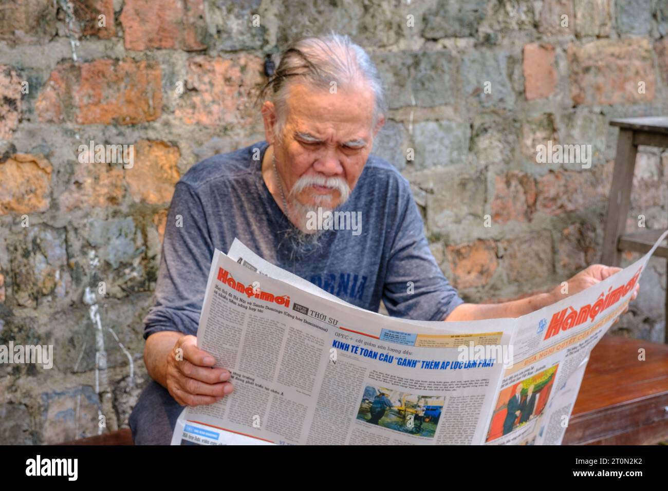 Hanoi, Vietnam. Homme âgé lisant un journal. Banque D'Images
