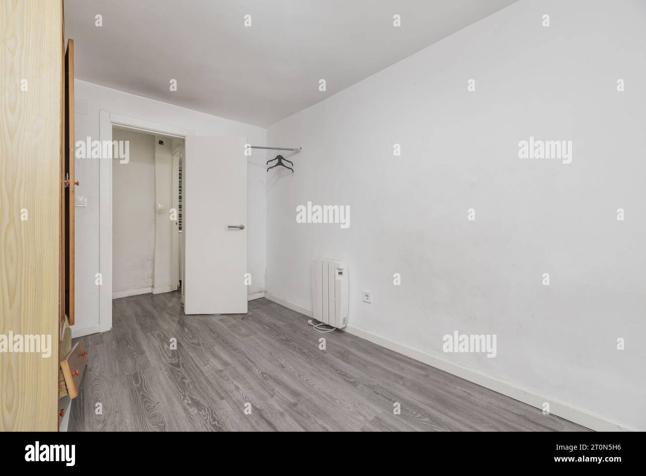 Chambre dans une maison vide avec sol stratifié gris, une vieille armoire et des murs peints en blanc Banque D'Images Chambre dans une maison vide avec sol stratifié gris, une vieille armoire et des murs peints en blanc Banque D'Images