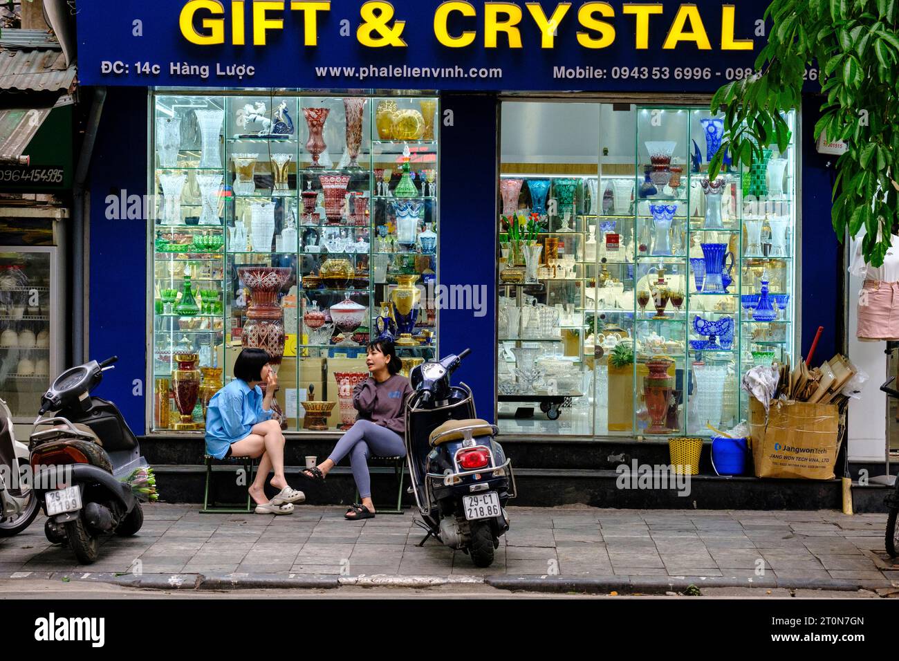 Hanoi, Vietnam. Femmes parlant devant une boutique de cadeaux et de cristaux. Banque D'Images