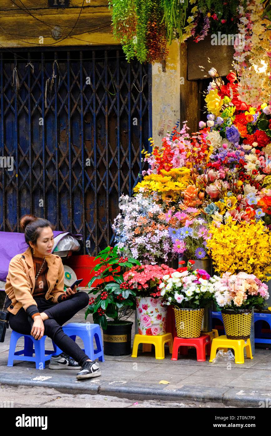 Hanoi, Vietnam. Hang Ma Street Shopkeeper avec des fleurs à vendre. Banque D'Images